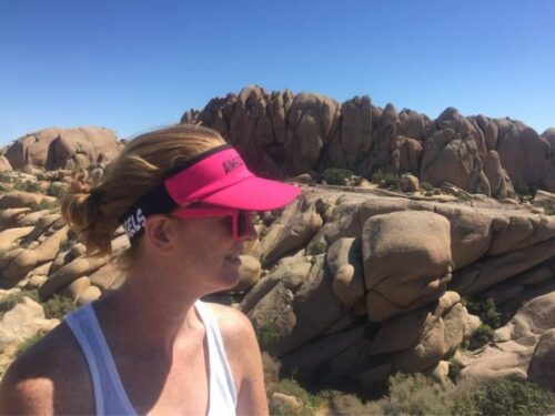 woman with a pink visor hat on a rocky background